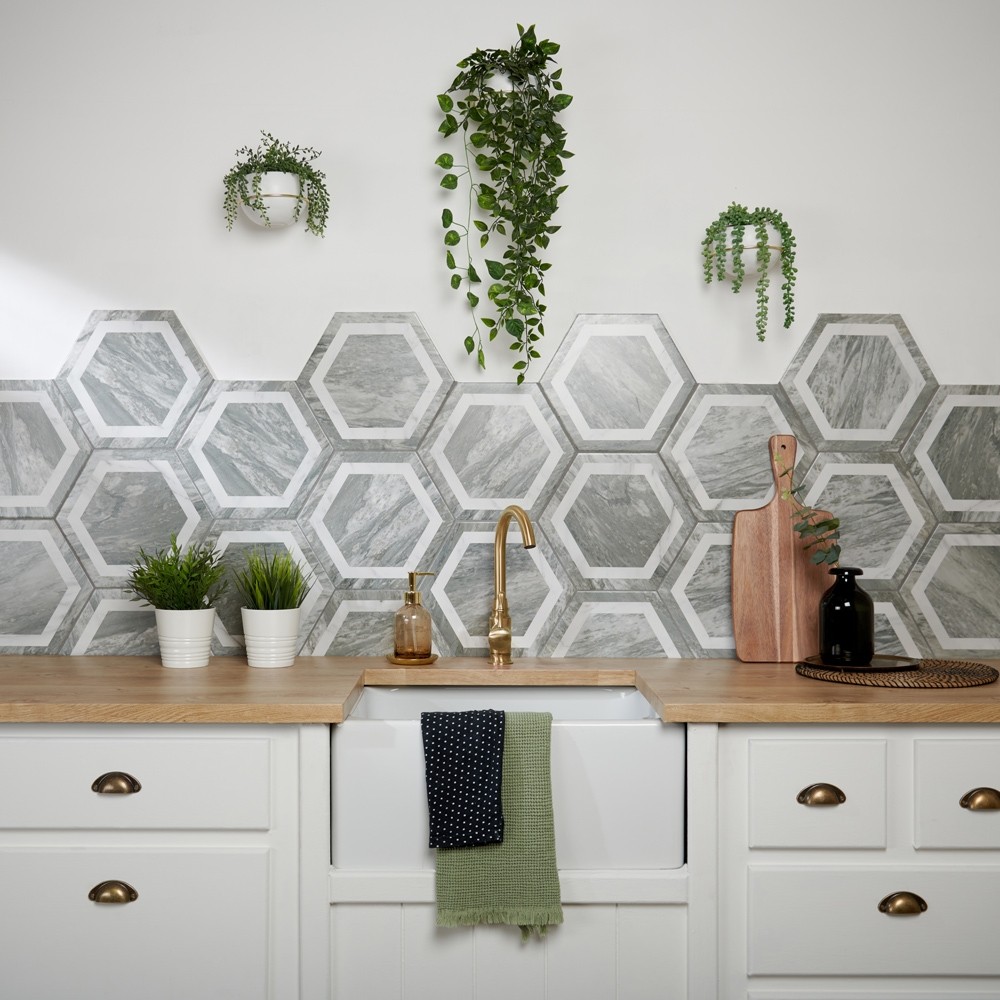 Modern hexagonal wall tiles across kitchen splashback with wood worktops and modern gold mixer tap on Belfast sink.