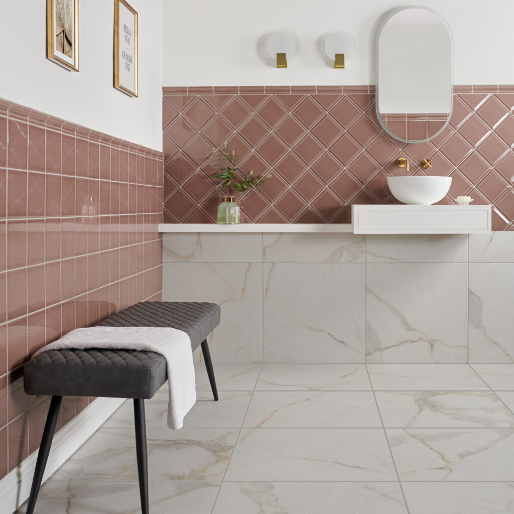 Capsule powder room dusky pink square ceramic tiles with a deep translucent glaze and bevelled edges paired with luxurious gold features and ruscello gold marble effect matt tiles 