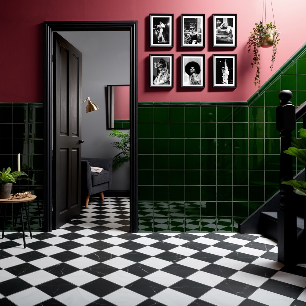 Chequer marble black and white tiles across floor space of hallway, deep green square tiles across wall to create panelling with vibrant pink paint above. 