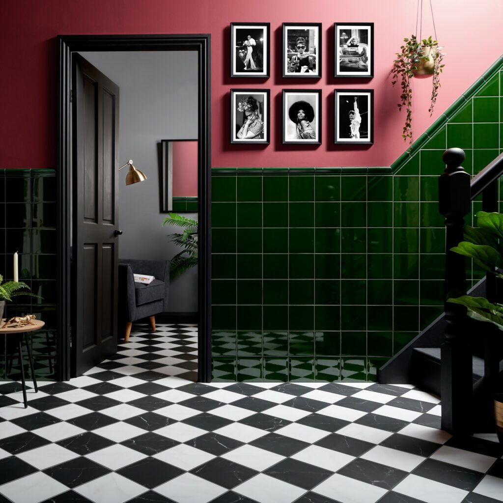 Colourful hallway display with capsule victorian green tiles paired with bright pink painted walls and black and white marble effect checkerboard tiles