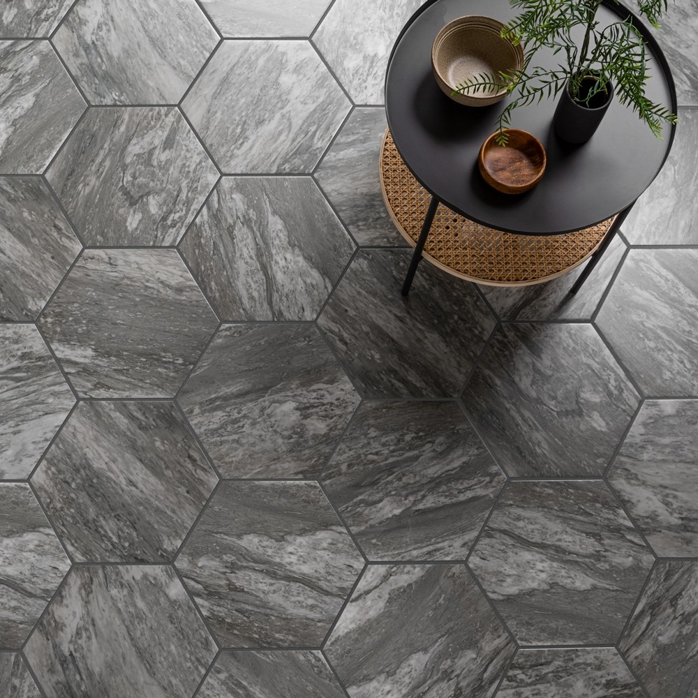 Modern grey hexagonal marble effect tiles across floor space with modern rattan side table and natural accessories. 