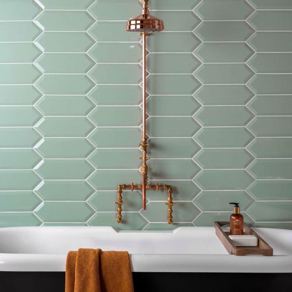 View of wall behind bath using mint green tiles and copper metal hardware. 