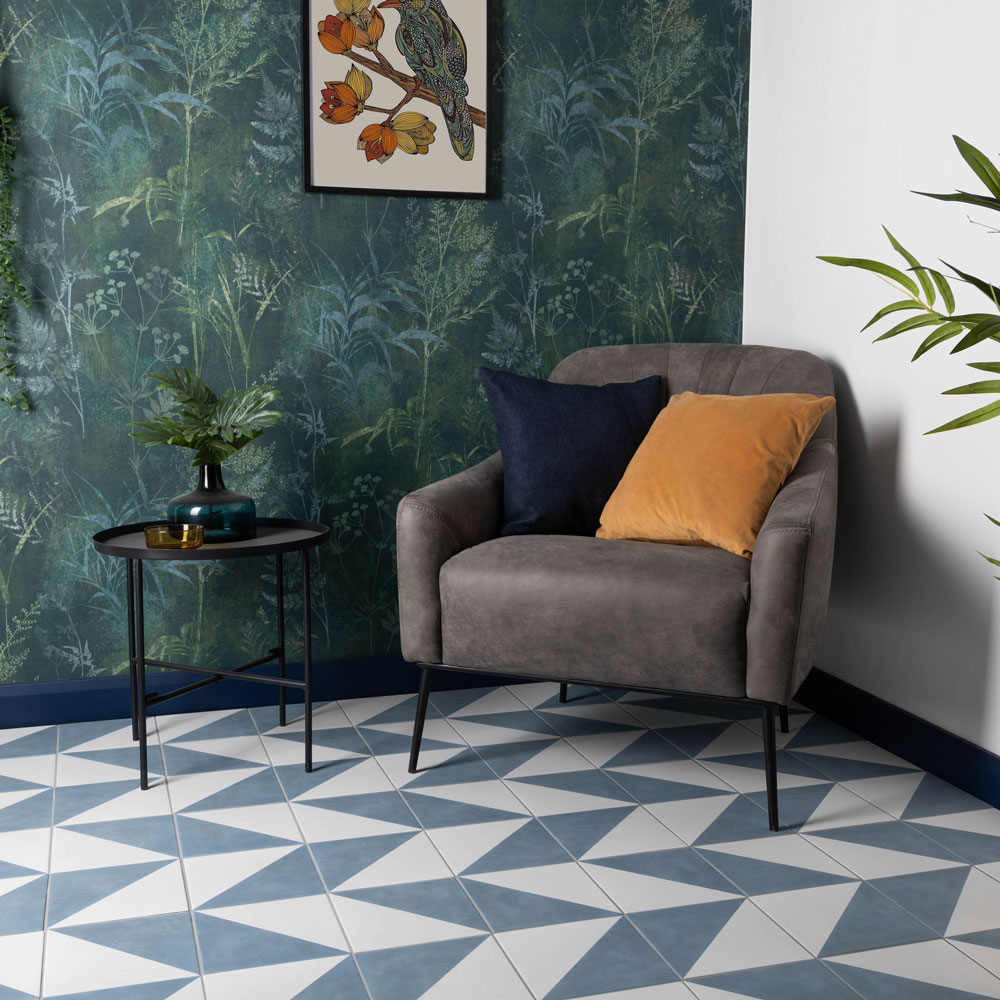 Geometric blue and white patterned floor in seating area with floral wallpaper. 