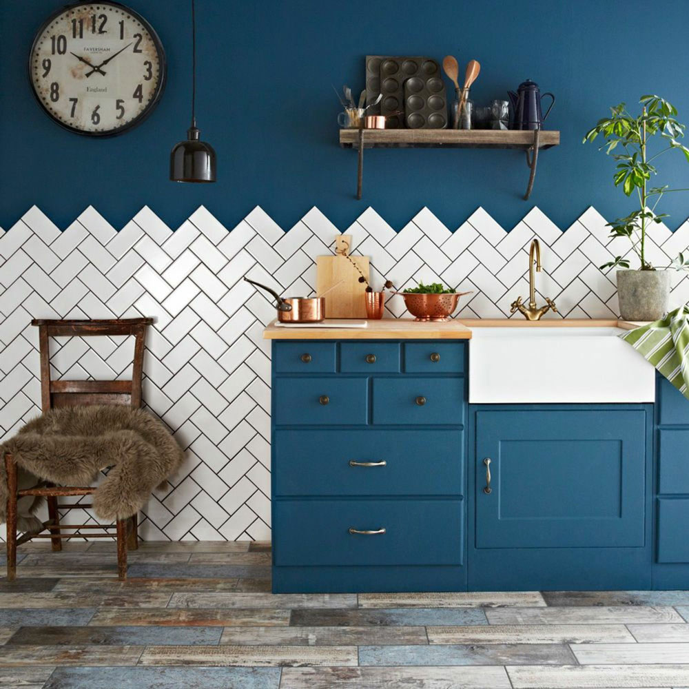 Kitchen splashback idea is white metro tiles against dark blue wall and dark blue cabinets.