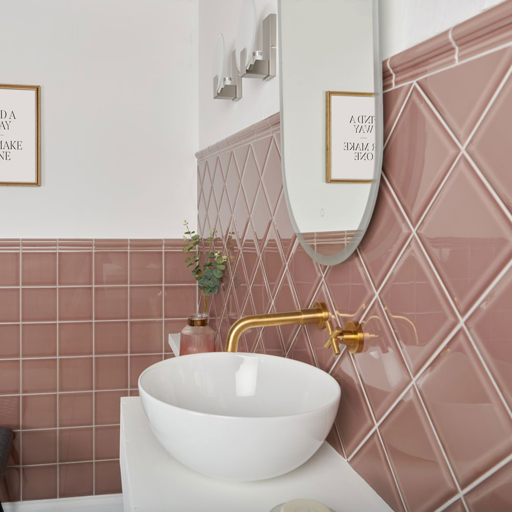 Muted pink bevelled tiles across sink area with white counter top sink and gold taps, adding colour to the idea of a home spa bathroom. 