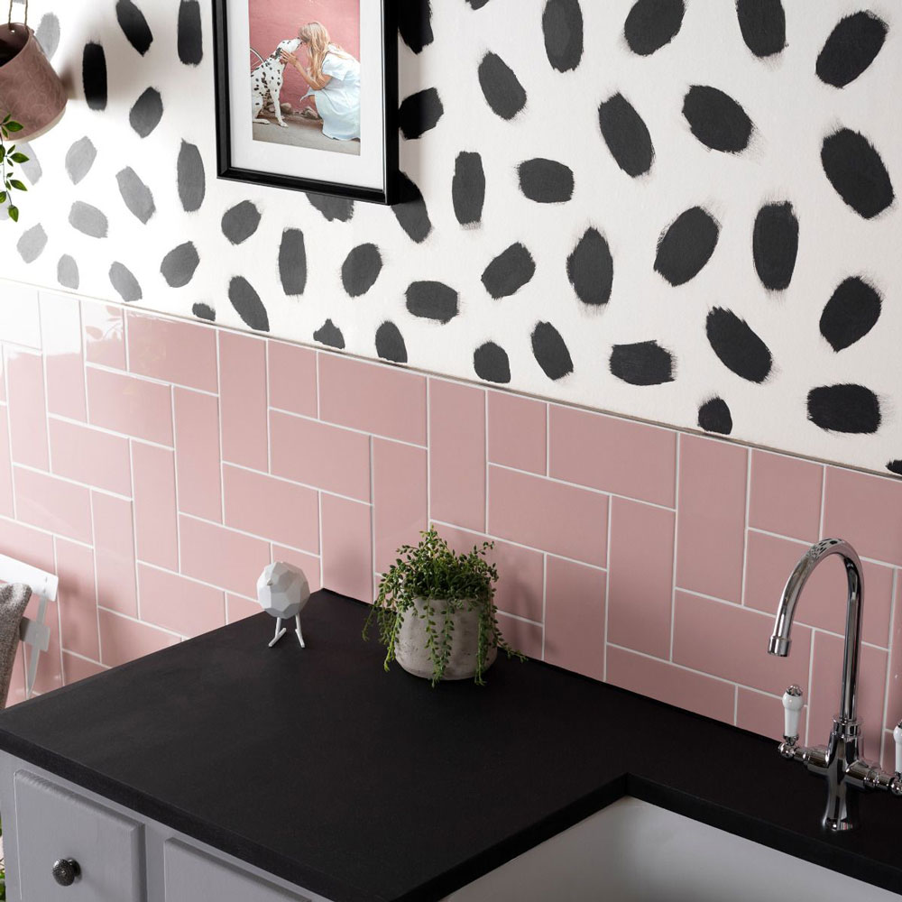 Kitchen colour idea includes pink splashback with grey cabinets and black and white detailed paint on wall above. 