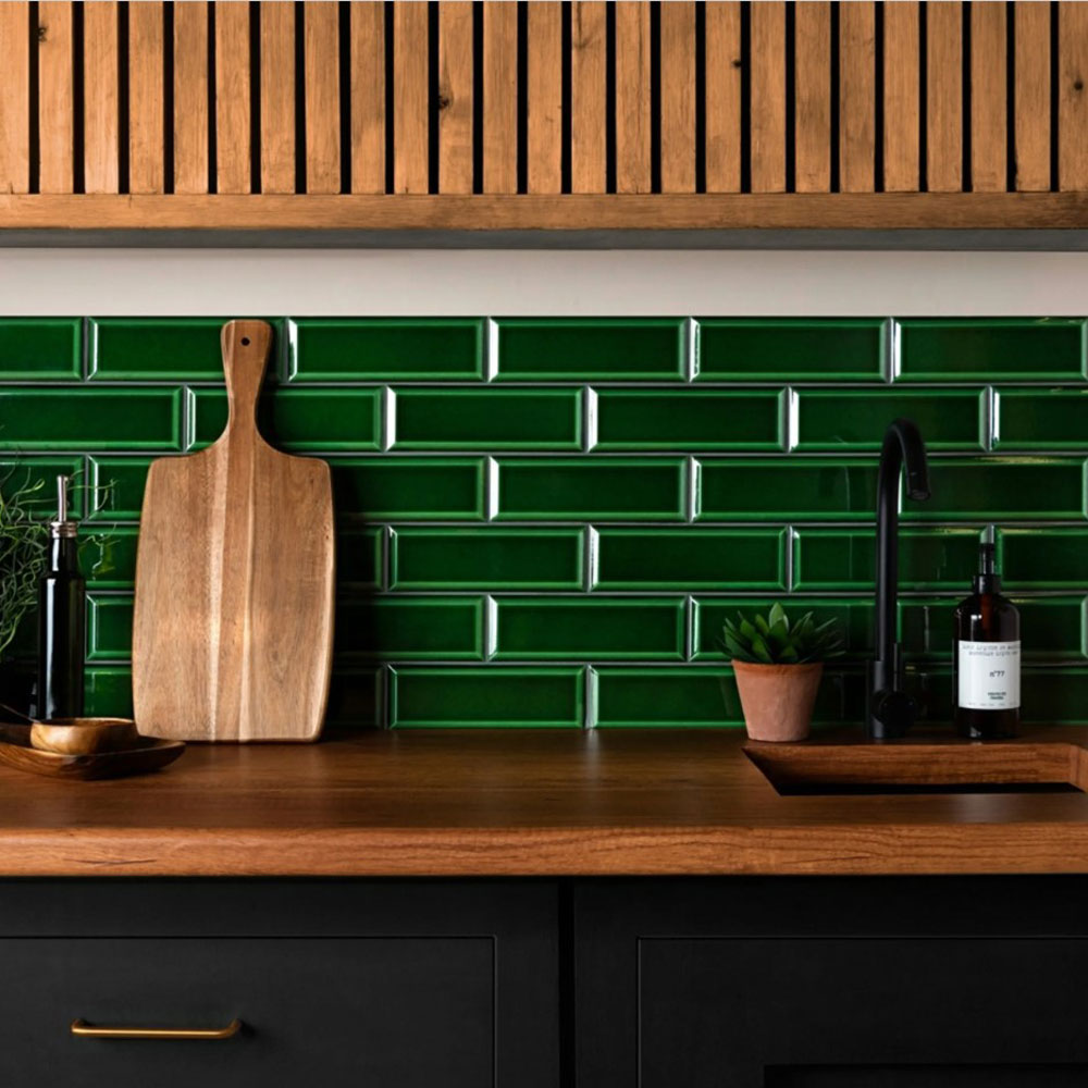 Green crackle glaze tiles are deployed across the splashback with wood worktop and cabinet above. 
