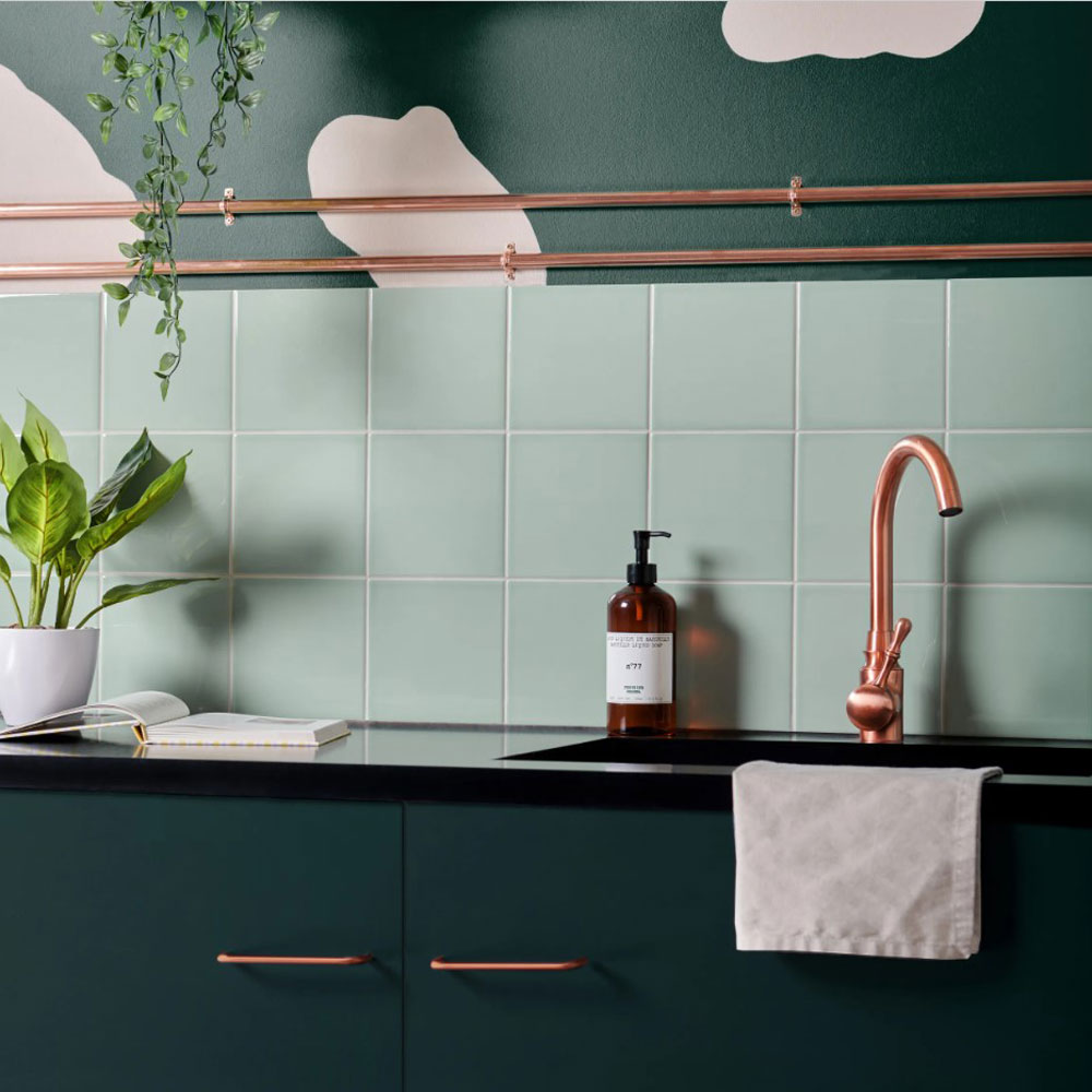 Pistachio green tiles across splashback with darker green cabinets. Copper hardware to contrast green. 