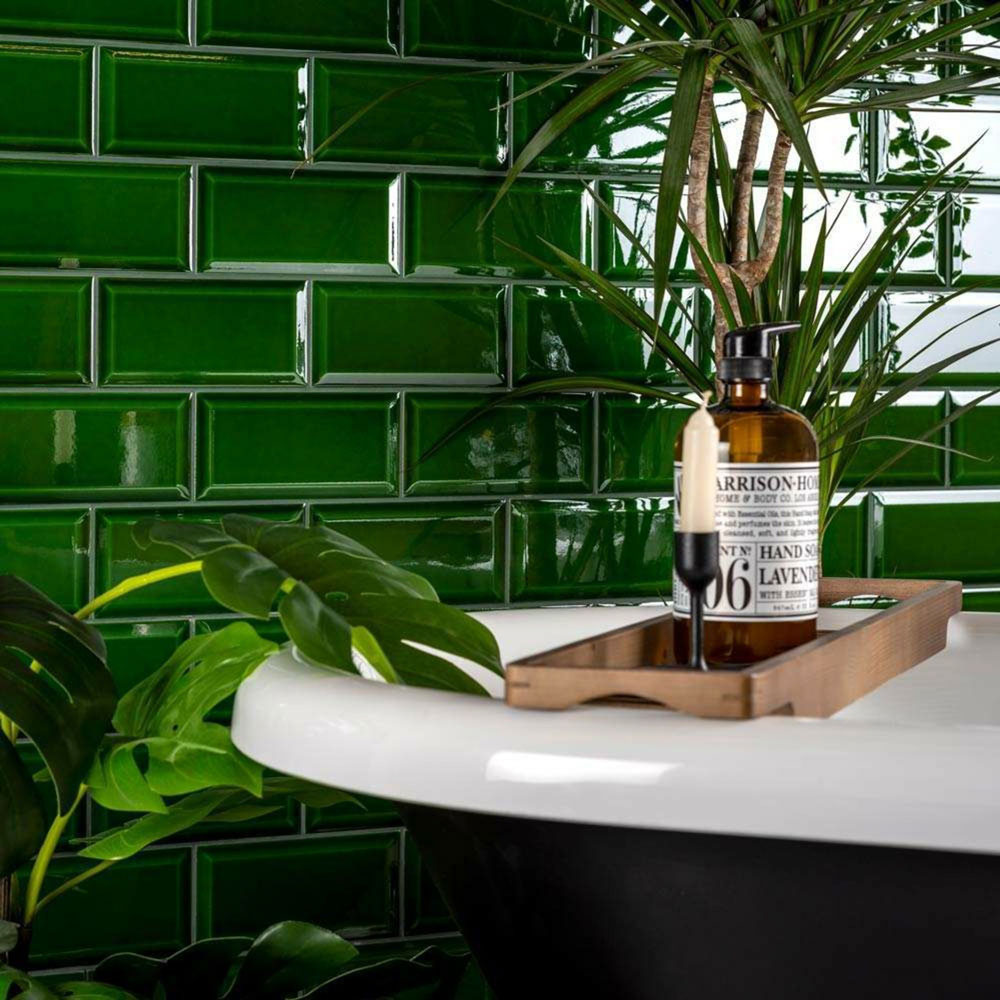 Victorian green metro tiles with crackle glaze on wall behind black and white bath. 