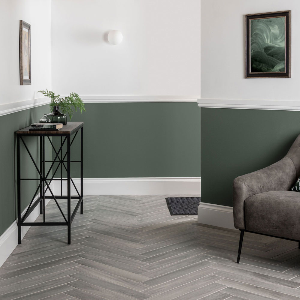 Deep green Paint along lower half of wall to act as panelling in the bedroom with white along the top and grey wood effect floor tiles. 