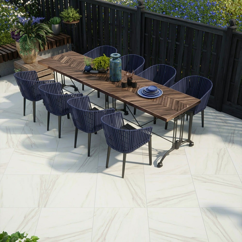 Outdoor dining space with wooden table and navy blue chairs, on modern marble effect outdoor patio tiles. 