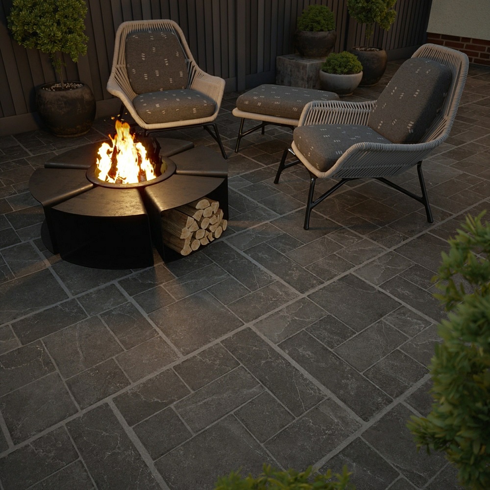 Dark grey outdoor paving slabs with modern black firepit and grey garden chairs.