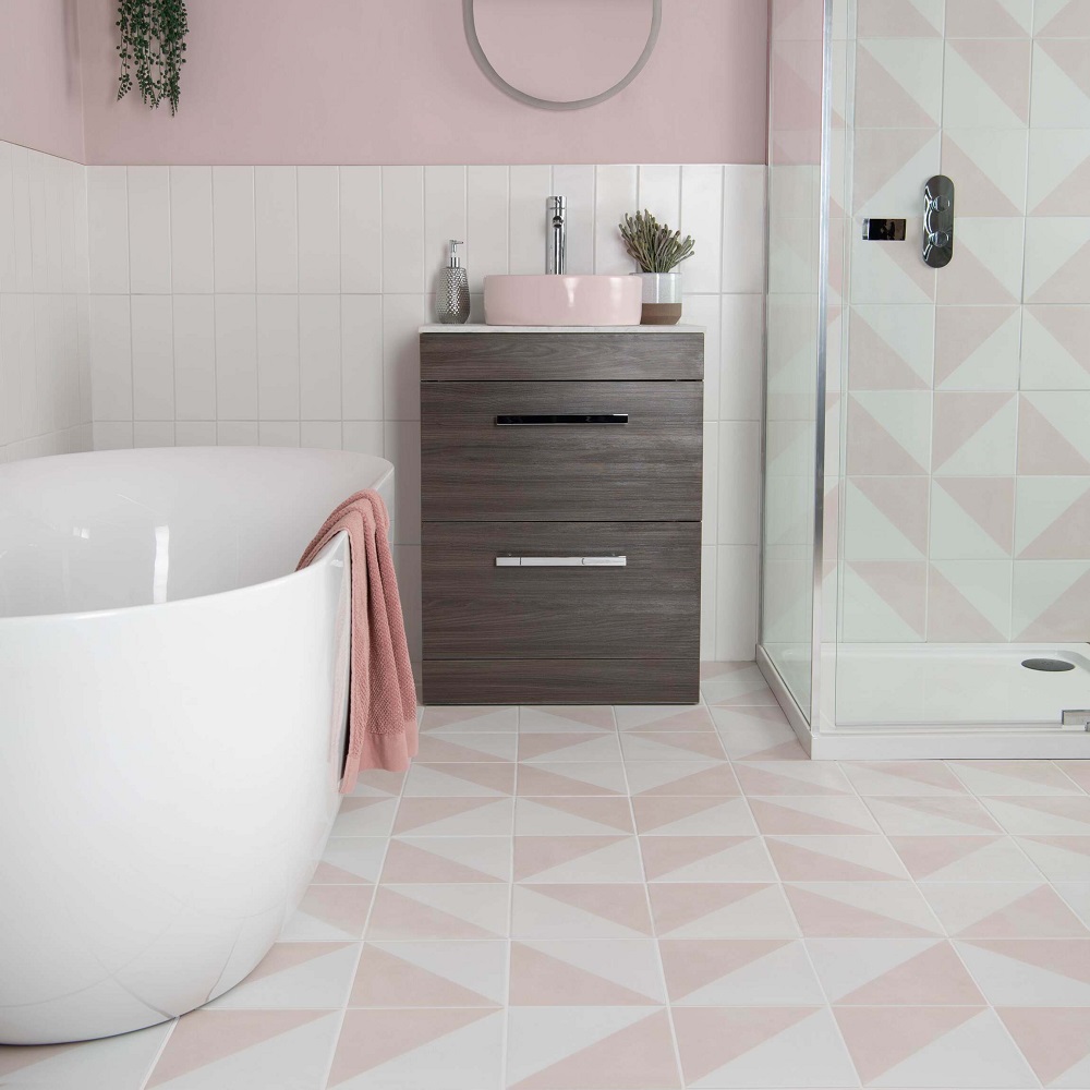 Pastel pink bathroom with geometric wall and floor tiles across shower and floor with white metro across bathroom splashback.