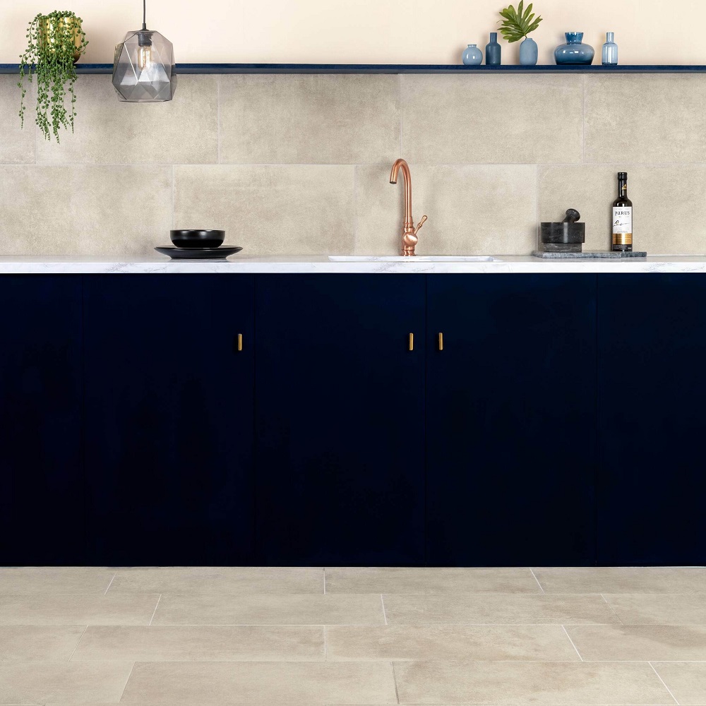Stone effect kitchen splashback and floors with navy blue cabinets and copper metal hardware on tap and handles. 