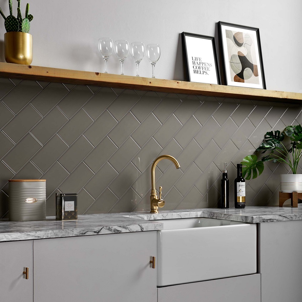 Floating shelf above grey kitchen space with gold metal hardware used across taps and handles on the cabinets.