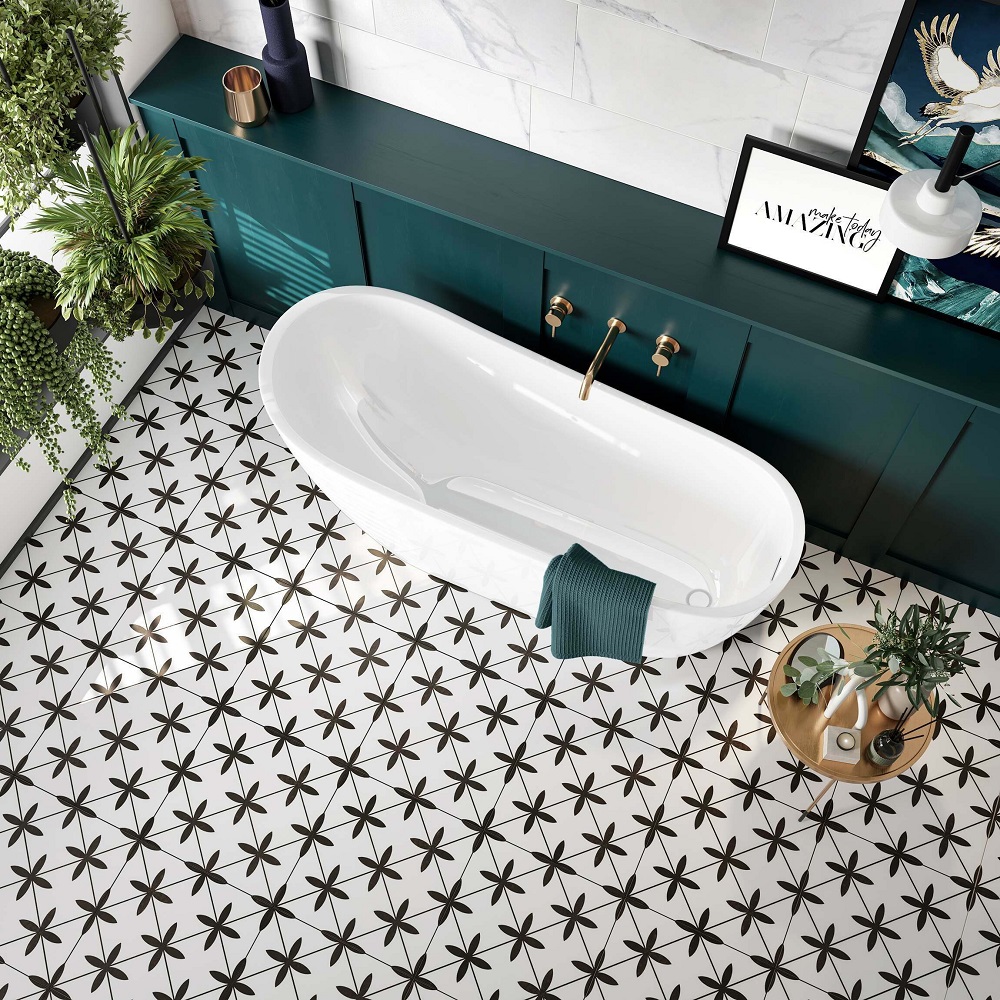 Black and white geometric floor tiles in bathroom space with green wood wall panelling and luxurious modern white freestanding bath. 