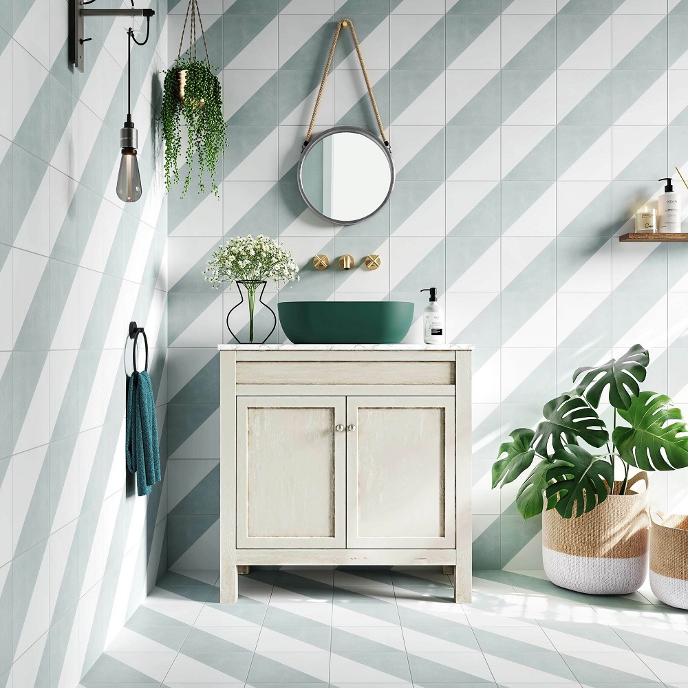 Geometric white and green pattern tiles across walls and floors of whole bathroom space. green accessories throughout the bathroom vanity area to complement.