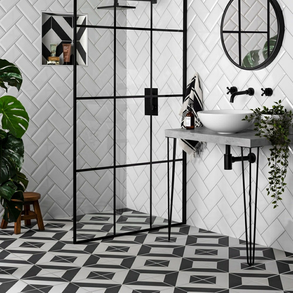 All black and white shower space with white and black geometric pattern floor tiles and matt black accents throughout whole space. 