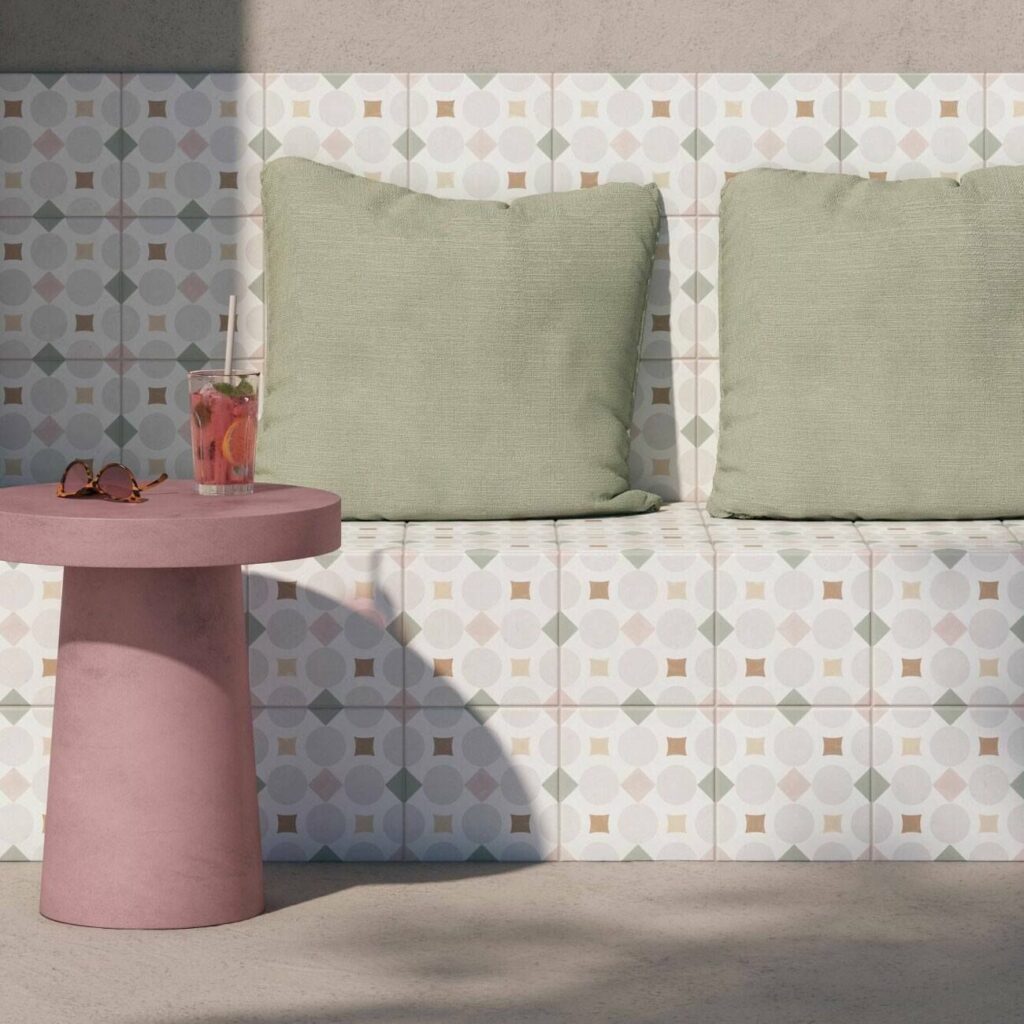 Pastel pink and green patterned tiles across outdoor seating area with pink side table and green cushions.