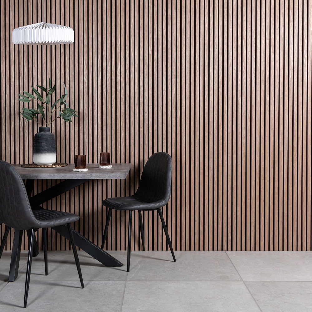 Table and chairs in dining room with light wood slat wall panels across the wall alongside, with glassware and a vase on the table top.