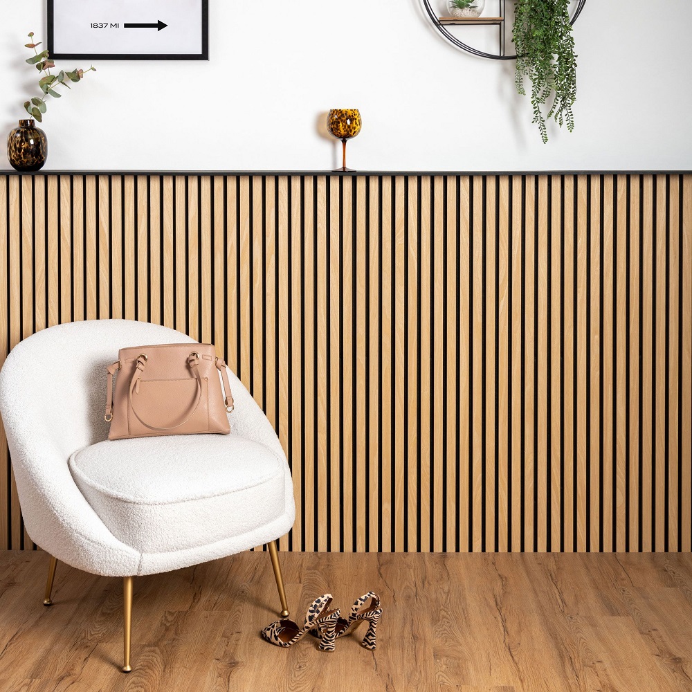 Half wood slat wall panels in cosy area with teddy bear white chair and various accessories around the space.