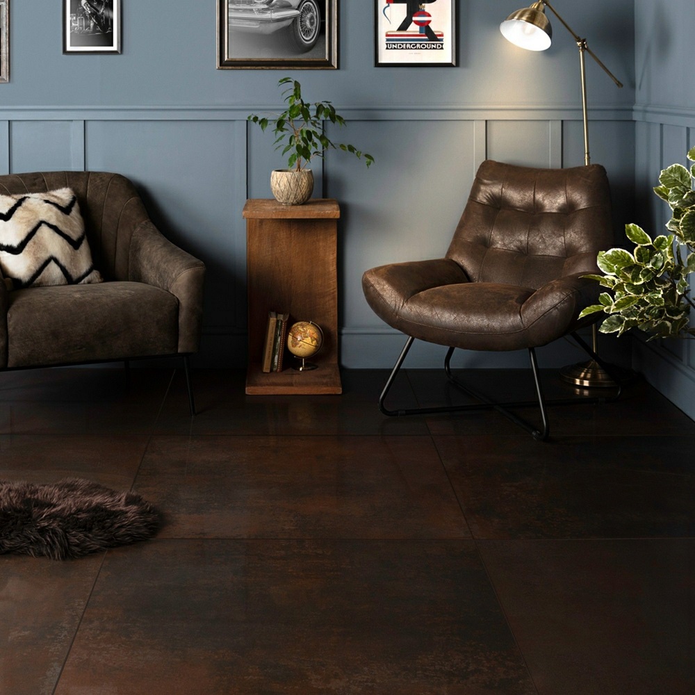 Dark living room scheme with rust effect floor tiles and deep blue wood wall panelling, creating cosy atmosphere. 