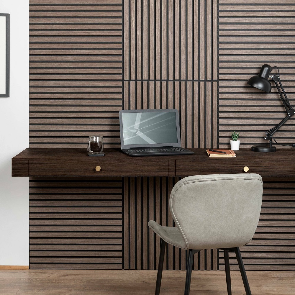 Home office setup with walnut square wood slat wall panels, floating desk, comfortable taupe chair, laptop, desk lamp, and minimalistic decor.