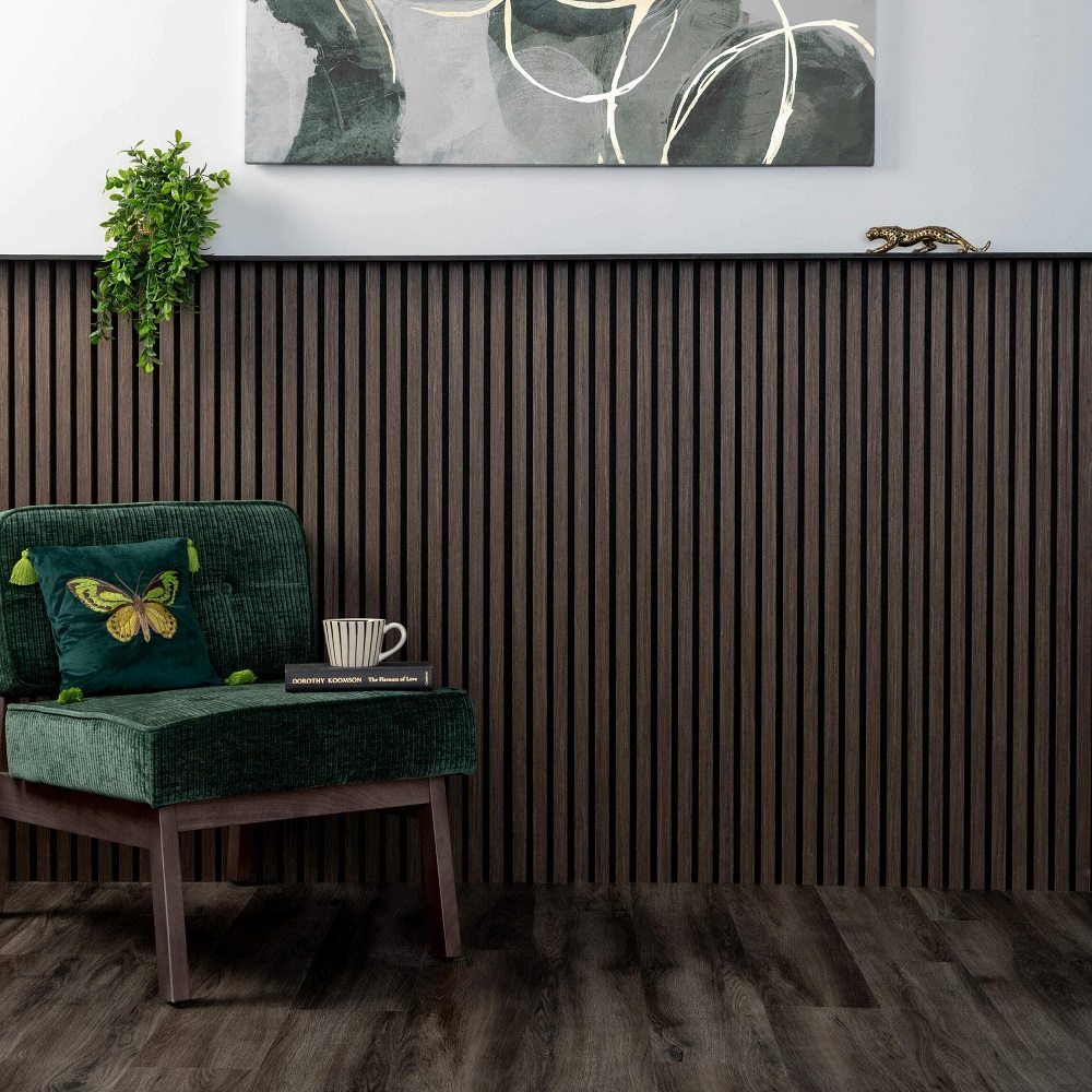 Sophisticated reading nook featuring Trepanel mini walnut wood slat panels on the wall, paired with dark wood flooring, enhancing the lush green armchair and nature inspired decor for a tranquil and stylish space. 