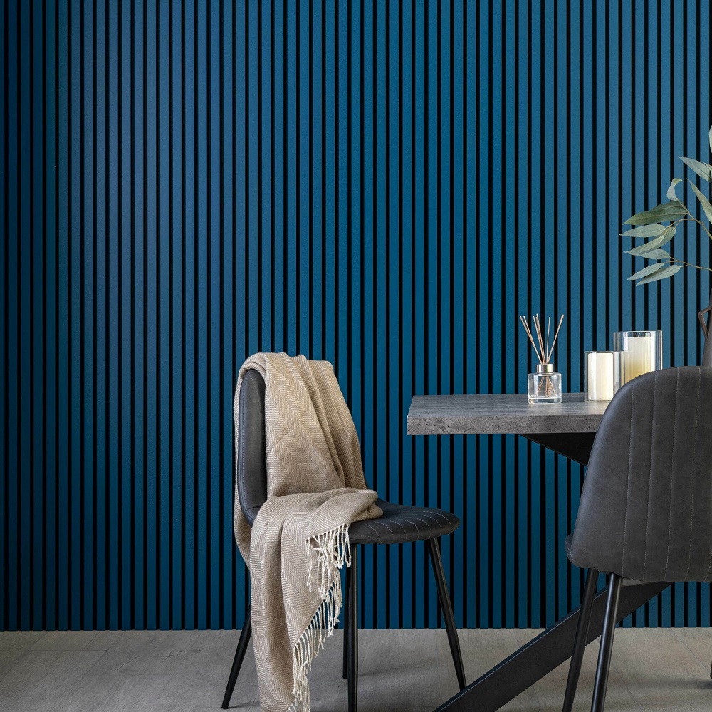 Modern decor with denim blue acoustic wood slat wall panels, a dark chair with a beige throw, and a concrete style table with candles.