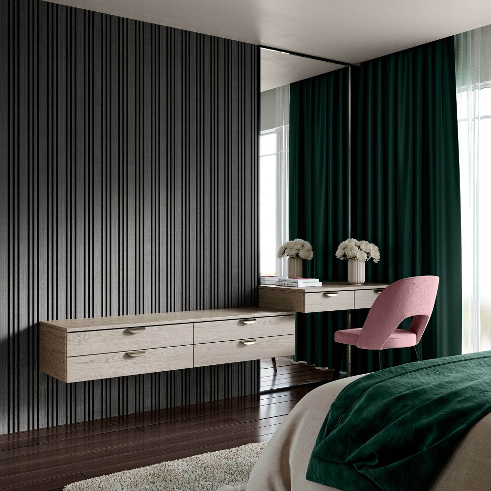An elegant bedroom showcasing a noir black multi-width panel wall and dark hardwood flooring. The room features a floating wooden console table with minimalist drawer pulls, complemented by a white vase. A plush pink chair adds a pop of colour, and the space is completed with luxe green emerald curtains, evoking a sophisticated and modern aesthetic. 