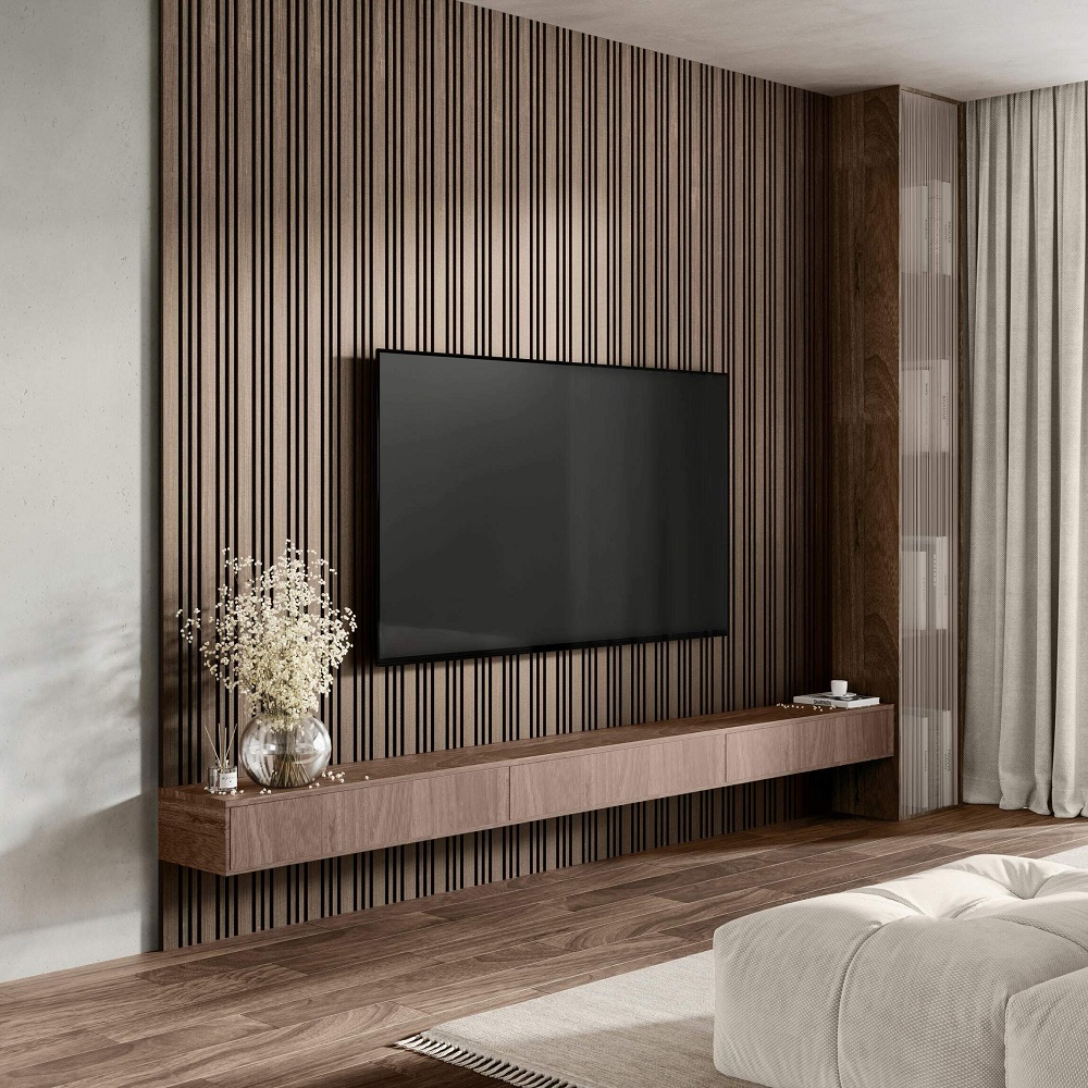 A modern living room wall accented with multi-width walnut panels and a mounted flat-screen TV. Below the television, a matching walnut floating shelf serves as a minimalist media console, adorned with a vase of dried flowers and a few small decorative items. Soft grey curtains provide a backdrop to this media area, and the rich wooden floor complements the natural aesthetic. 